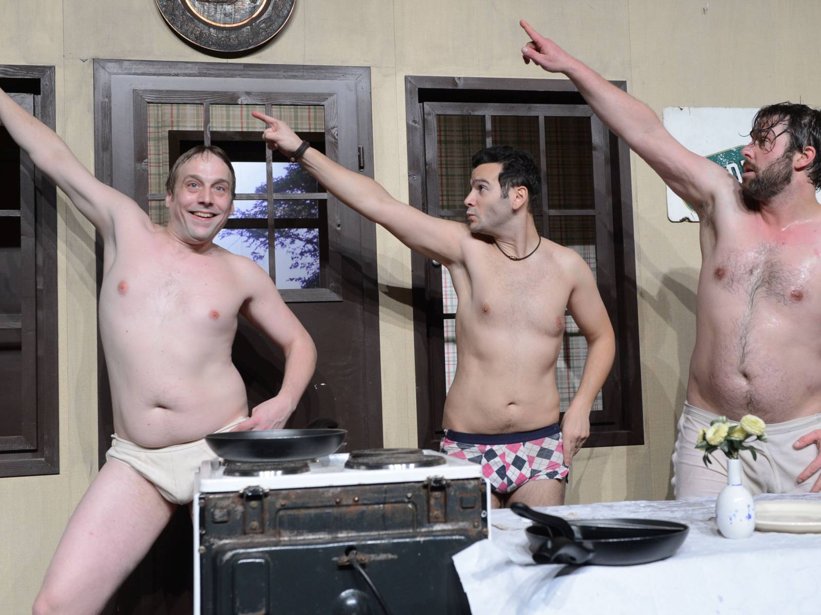 Drei Männer in Unterwäsche posen auf einer Bühne